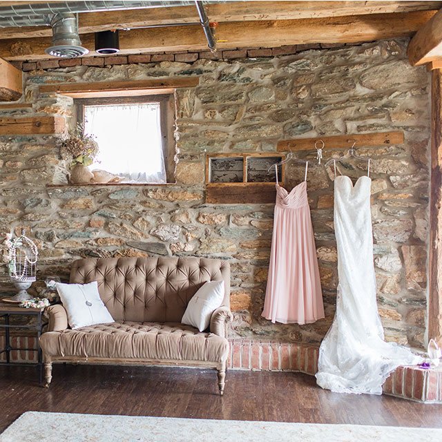 The bridal suite, with a tufted sofa, stone walls and dresses hanging